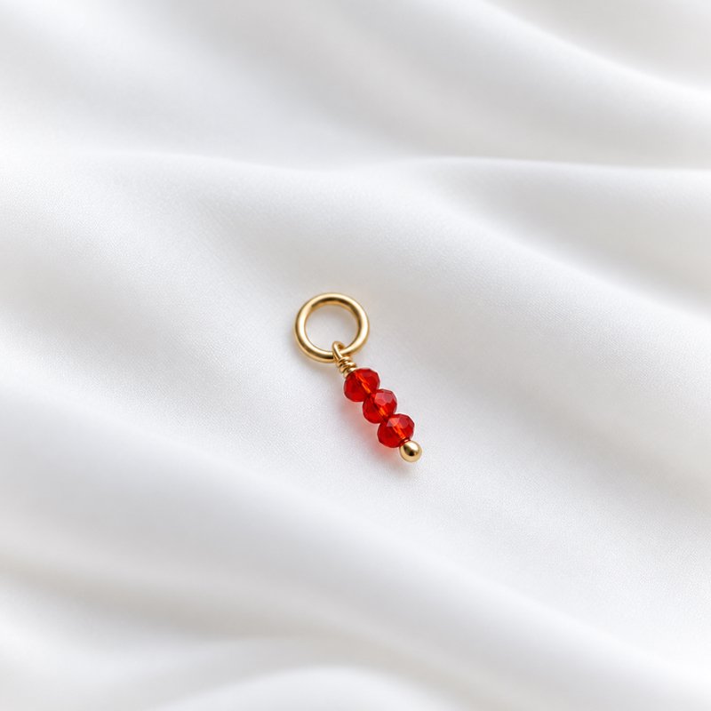Charm i guld med 3 sm� r�da glasp�rlor