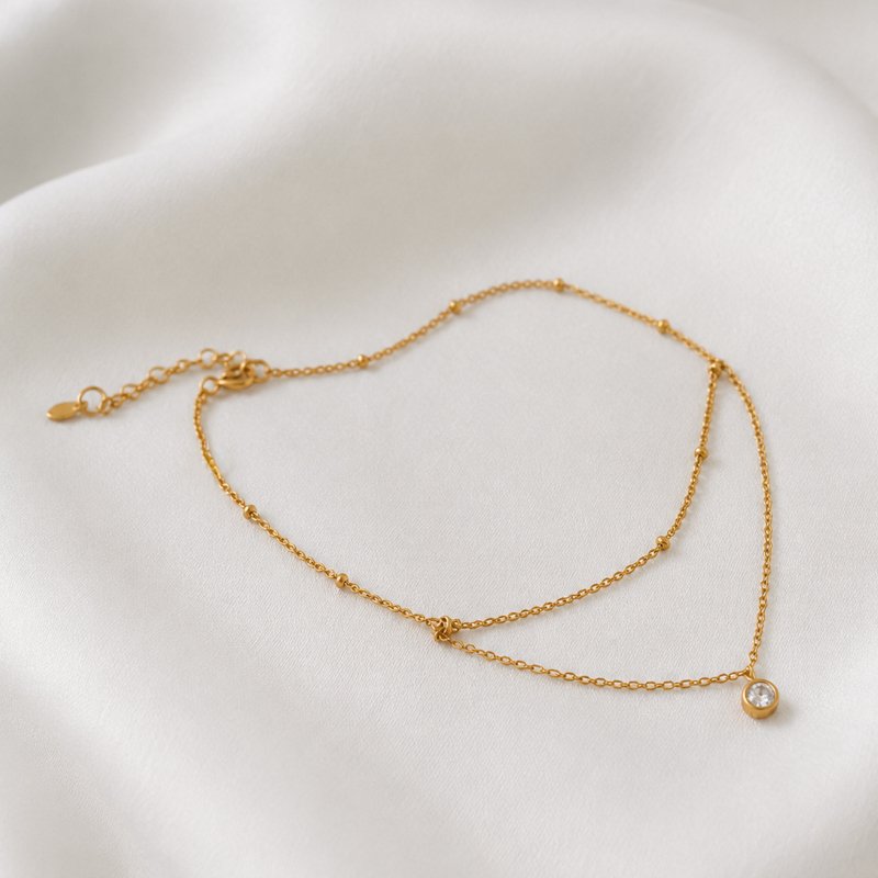 "Kaja" gold ankle chain with gold balls and white stone