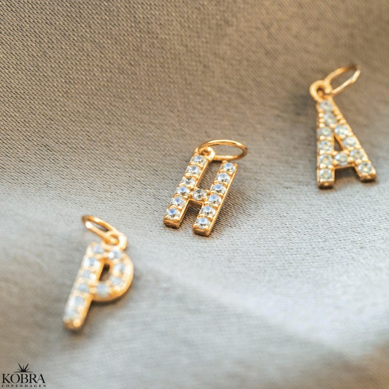 "Alias" gold letter with white stones (charm)