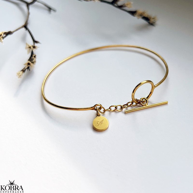 "Loop" guld armbnd med bidsells og lille guld amulet med personlig gravering