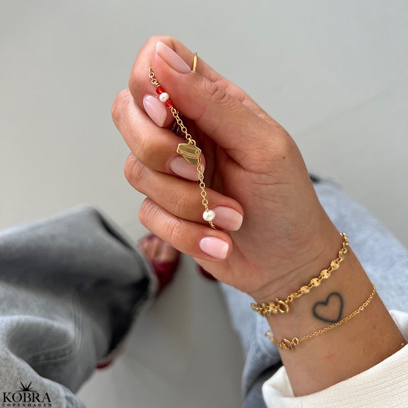 Studenter armbnd i guld med hue-vedhng og rde perler