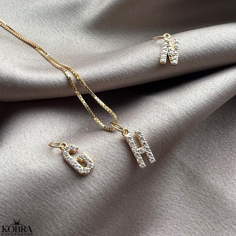 "Alias" gold letter with white stones (charm)