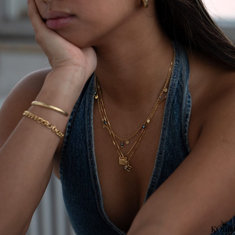 "Pittioni" guld perlekde med bl ferskvandsperler og sm amuletter