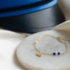Studenter armb�nd i guld med hue-vedh�ng og m�rkebl� perler