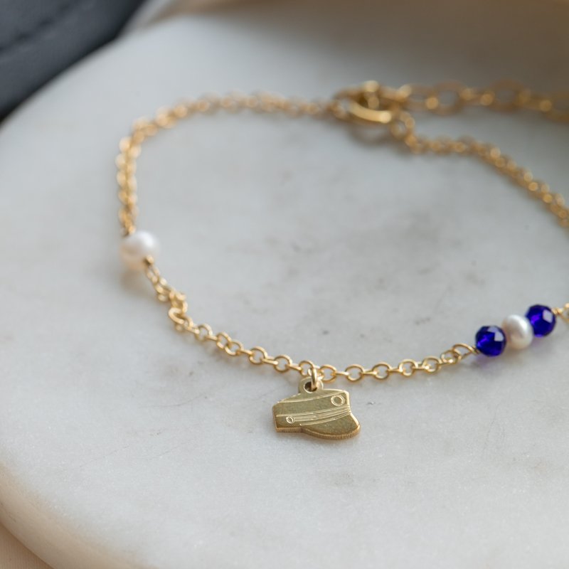 Studenter armb�nd i guld med hue-vedh�ng og m�rkebl� perler
