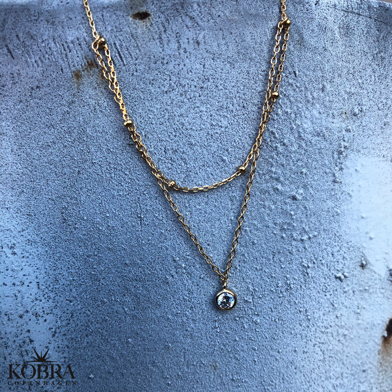 "Kaja" guld ankelkde med guldkugler og hvid sten