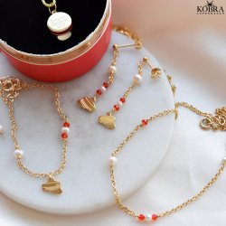 Studenter armbnd i guld med hue-vedhng og rde perler