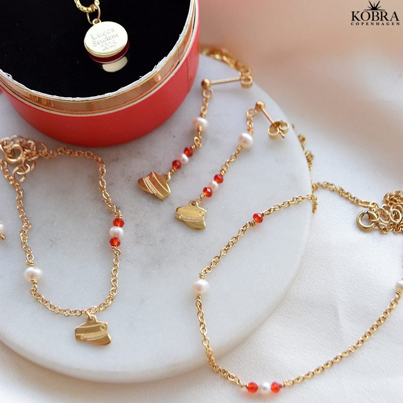 Studenter armbnd i guld med hue-vedhng og rde perler