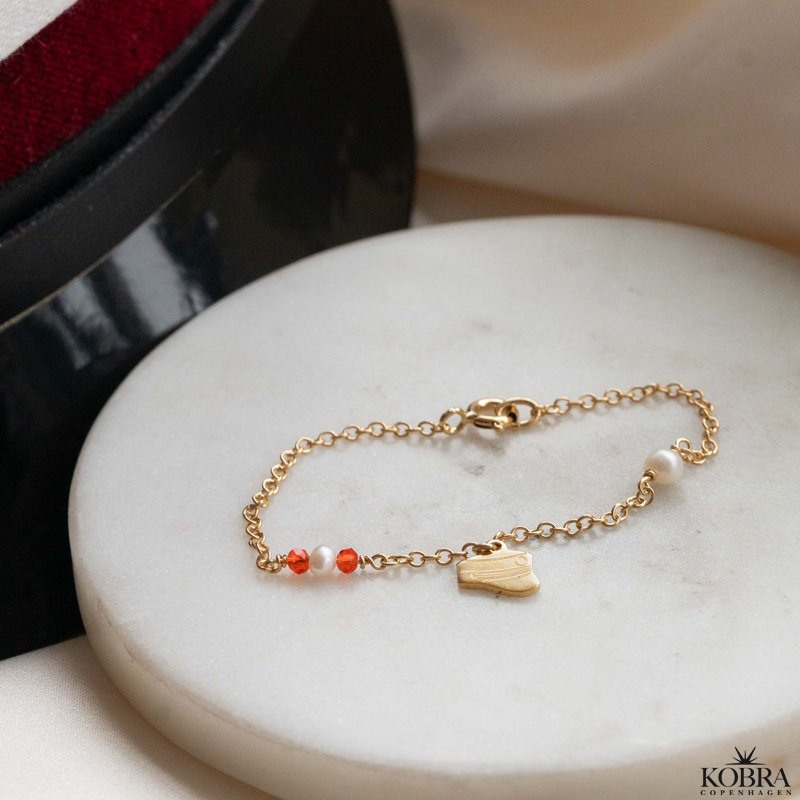 Studenter armbnd i guld med hue-vedhng og rde perler